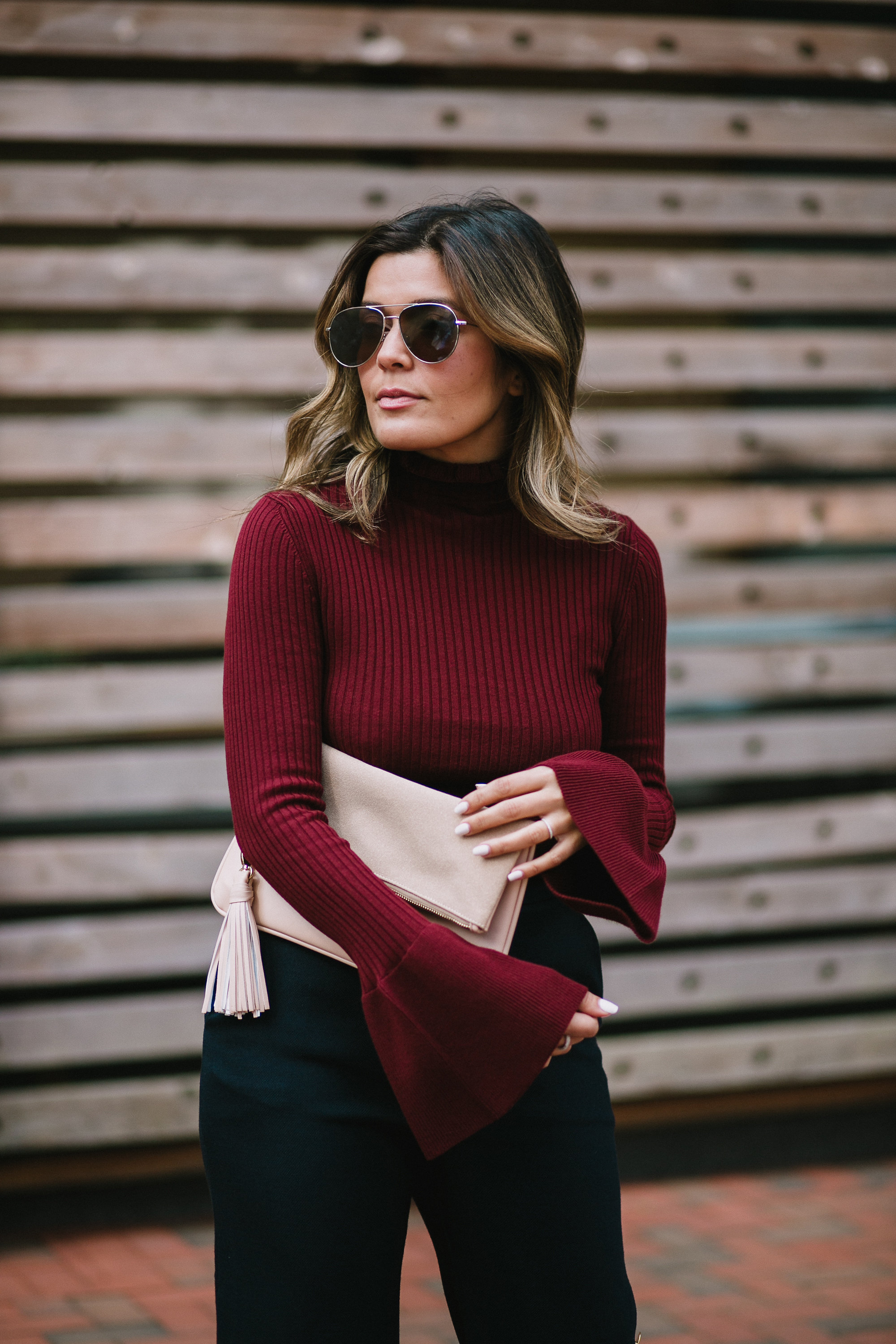 Blogger Sara Azani of Style MBA wears Wide Leg Trousers, a red H&M Sweater, nude Schutz Sandals, and a beige Who What Wear for Target Clutch.